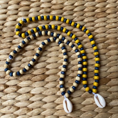 Colar de contas azuis, amarelas e brancas com pendente de concha sobre tecido de palha trançada