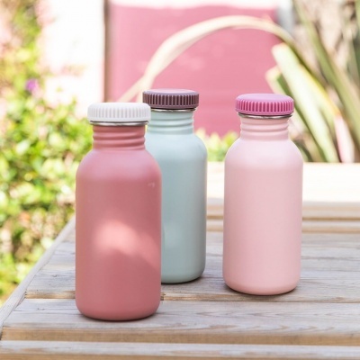 três garrafas reutilizáveis coloridas sobre mesa de madeira ao ar livre