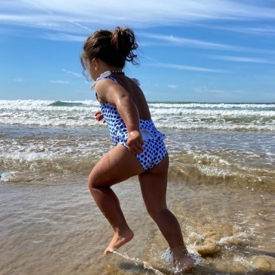 Fato de banho infantil azul com bolinhas brancas na praia