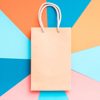 Saco de papel castanho com alças de corda branca sobre fundo colorido