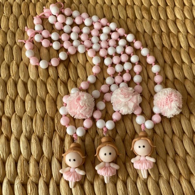 Colares com contas rosa e branco, pompons e pendentes de bonecas bailarina sobre ráfia