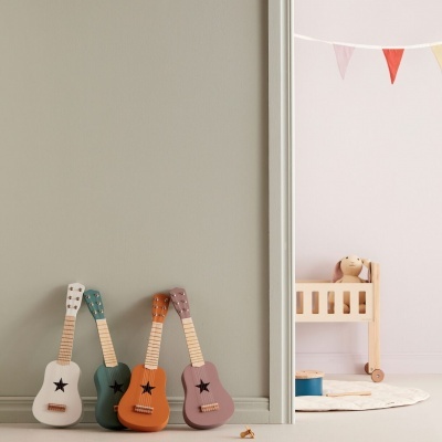 Quatro guitarras decorativas coloridas encostadas numa parede ao lado de um quarto infantil
