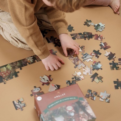 Criança a montar puzzle colorido com caixa sobre superfície bege