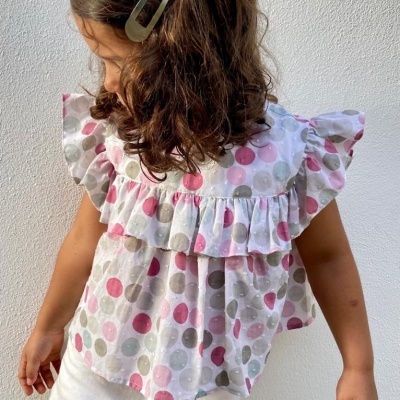 Blusa de criança com bolinhas coloridas e folhos, vista de perfil