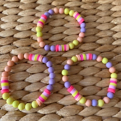 Três pulseiras elásticas coloridas sobre superfície de fibras naturais entrelaçadas