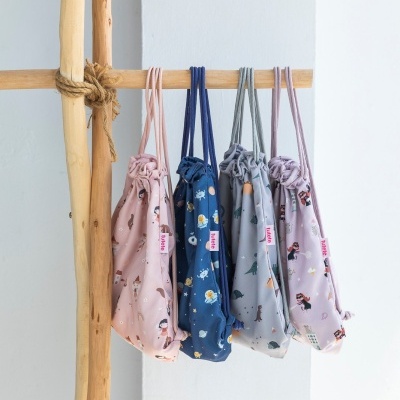 Cinco mochilas de tecido coloridas com estampados diversas penduradas num cabide de madeira