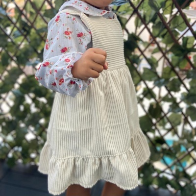 Vestido branco riscado com folho usado sobre camisa estampada de flores.