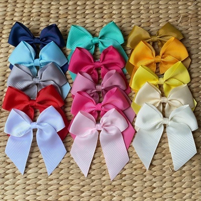 Presilhas de cabelo laço variadas em cores vibrantes sobre superfície trançada