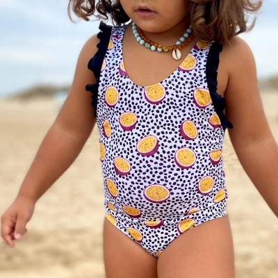 Fato de banho infantil com estampa de maracujás e polka dots na praia