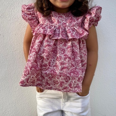 Blusa rosa com padrão de cachecol e folhos de menina com calças brancas