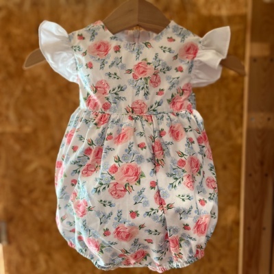 Macacão de bebé floral com mangas brancas em cabide de madeira