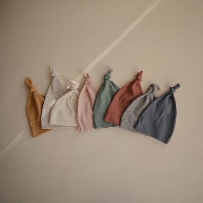 Sete gorros de malha coloridos com nó na ponta alinhados