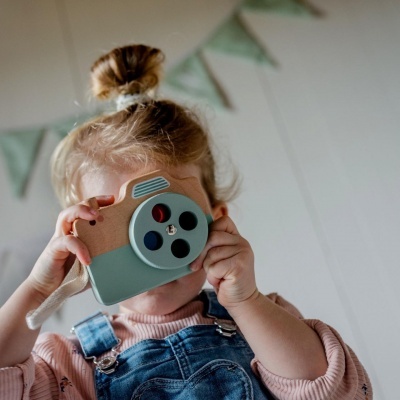 Criança a brincar com câmara fotográfica de brinquedo em madeira