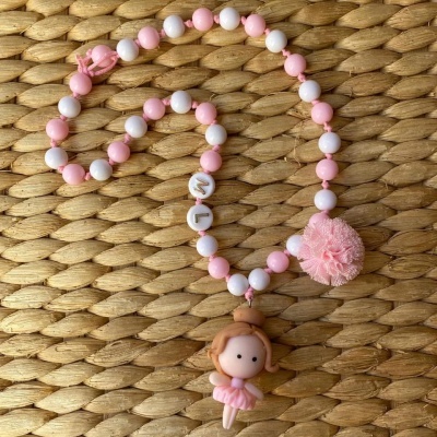Colar rosa e branco com boneca bailarina e pompom sobre palha