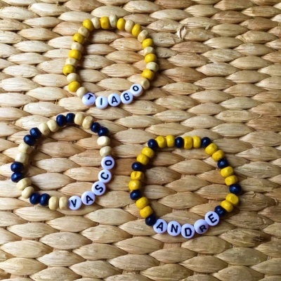 Três pulseiras de contas coloridas e letras em superfície de fibras naturais