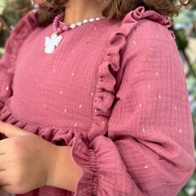 Vestido rosa com babados e detalhes dourados, colar de contas com pendente de borboleta