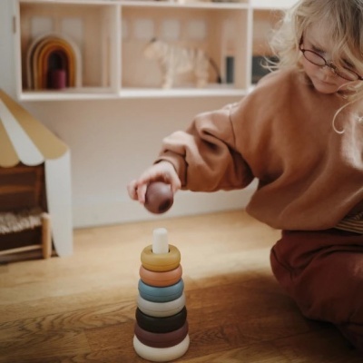 Brinquedo de empilhar anéis coloridos em madeira com criança a brincar no chão