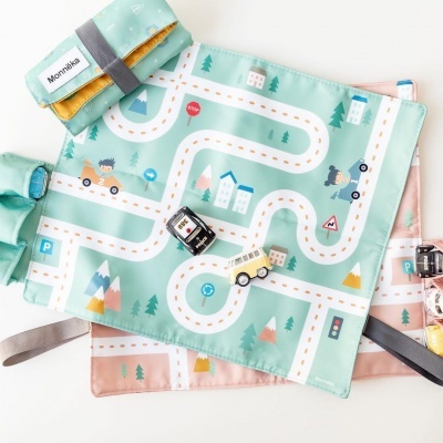 Tapete infantil de tecido com padrão de estradas, carros e casas em tons pastel.