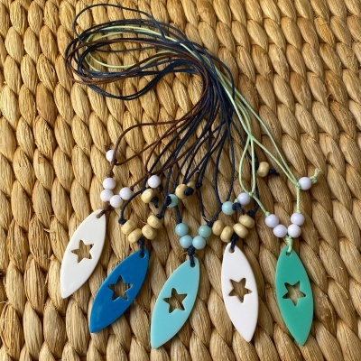 Colares com pendentes coloridos com recorte em forma de estrela sobre tecido rústico castanho
