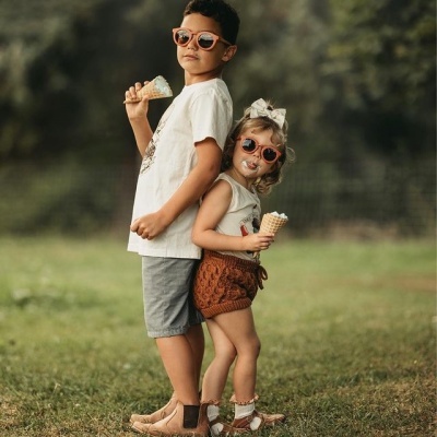 Duas crianças ao ar livre com óculos de sol e gelados