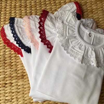 Bodies infantis brancos com gola rendada colorida em cima de superfície trançada