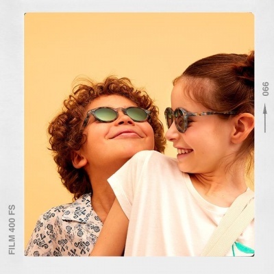 Crianças sorrindo com óculos de sol em fundo amarelo