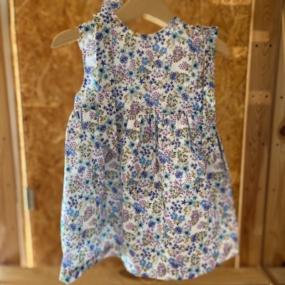 Vestido infantil floral colorido pendurado em cabide de madeira