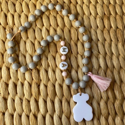 Colar de contas cinza, rosa e branco com letras 'M' e 'A' e pendente de urso branco com tassel rosa.