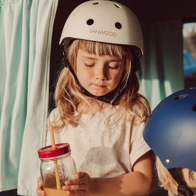 Criança com capacete branco BANWOOD segurando copo com tampa vermelha e canudo