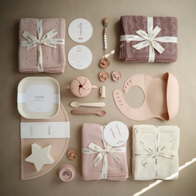 Conjunto de produtos para bebé em tons de rosa e branco sobre fundo bege