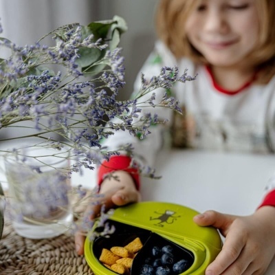 Tigela verde com frutas e flores secas sobre mesa branca