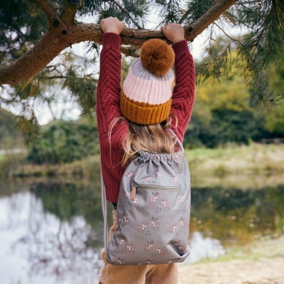 Mochila cinzenta com padrão floral usada por criança junto a lago