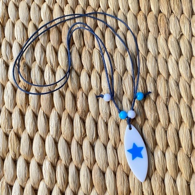 Colar com pendente branco e azul sobre superfície tecida bege