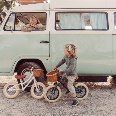 Crianças com bicicletas infantis com cestos de vime ao lado de carrinha clássica verde claro