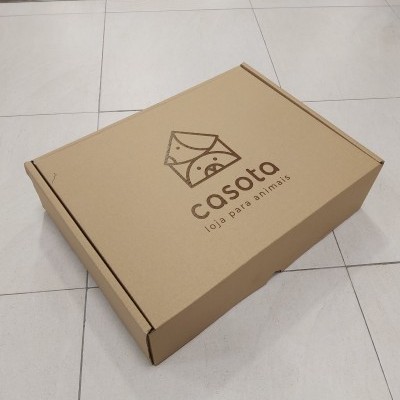 Caixa de cartão com logótipo casota sobre chão de azulejos