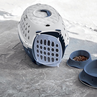 Transportadora cinza e azul para animais com comedouros ao lado