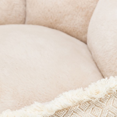 Assento redondo estofado bege claro com almofada decorativa bege com franjas.