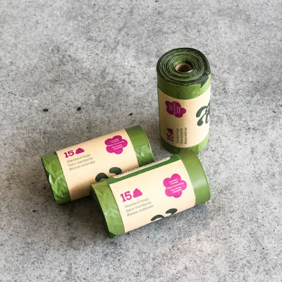 Três rolos de sacos verdes com etiquetas de papel