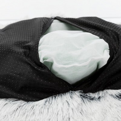 Colchão redondo com capa preta perfurada sobre superfície felpuda cinza