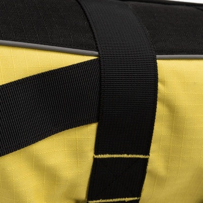 Detalhe de saco amarelo com alça preta e topo preto.