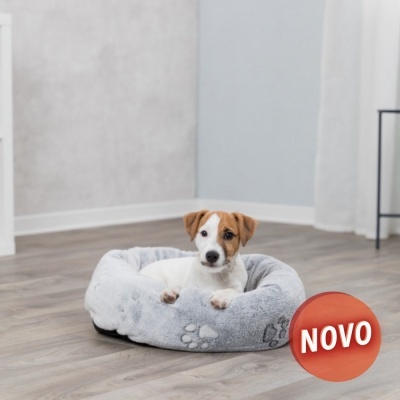 Cama cinza claro redonda felpuda com padrão de patas e cão sentado dentro