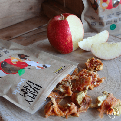 Pacote de snacks de frutas desidratadas com maçã cortada e fatias sobre superfície de madeira