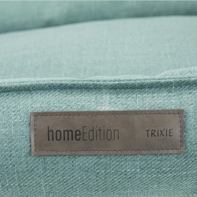 Etiqueta 'homeEdition TRIXIE' numa almofada de tecido azul claro