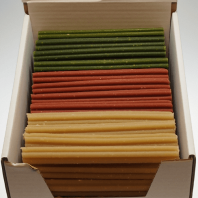 Caixa aberta com varas de cera verdes, vermelhas e bege organizadas em camadas