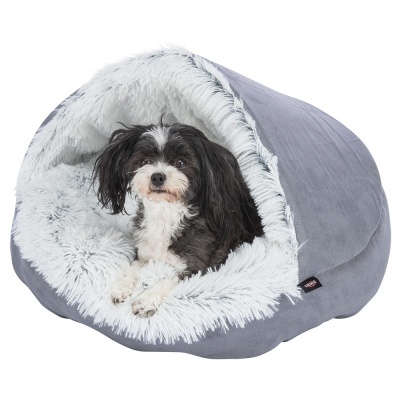 Cão preto e branco deitado numa cama de tecido cinzento com interior de pêlo sintético branco felpudo.