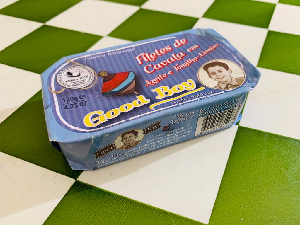 Filetes de Cavala em Azeite e Tomilho- Limão - Good Boy Lata azul de filetes de cavala Good Boy em azeite com limão sobre mesa xadrez verde e branco