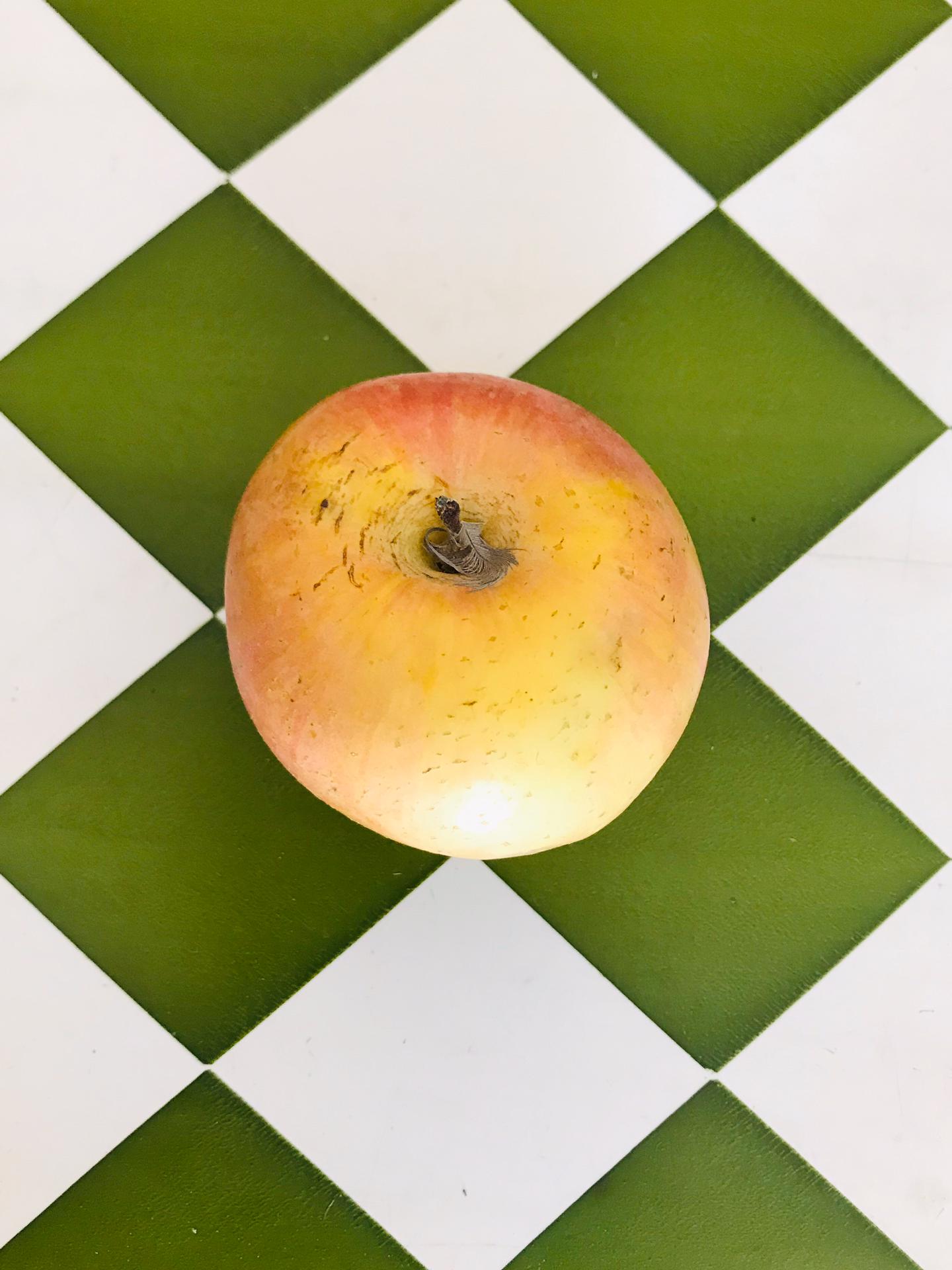 Maçã Gala (unidade) Maçã amarela e vermelha sobre fundo xadrez verde e branco