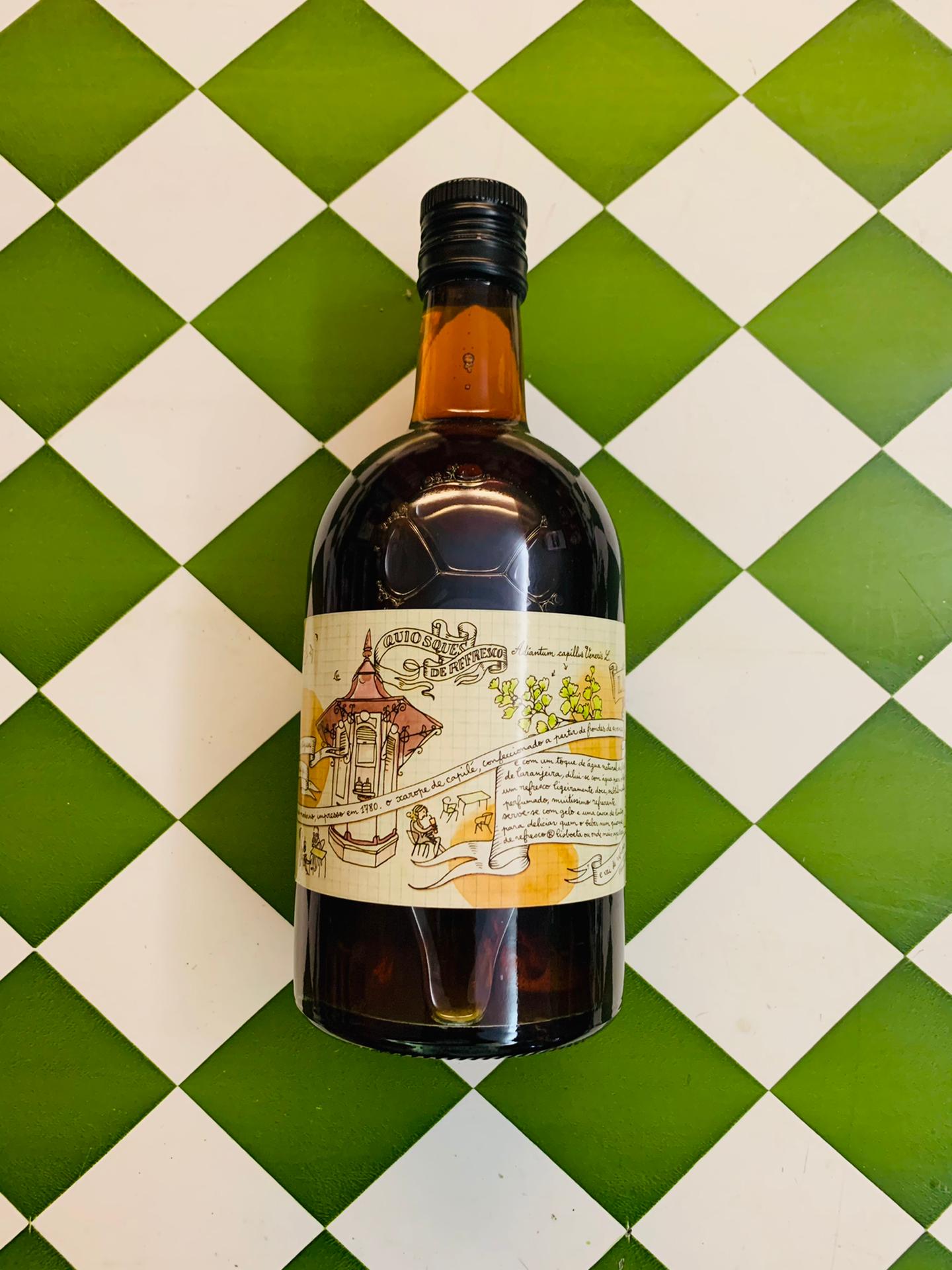 Xarope de Capilé Garrafa de vidro escuro com rótulo artístico sobre superfície xadrez verde e branco
