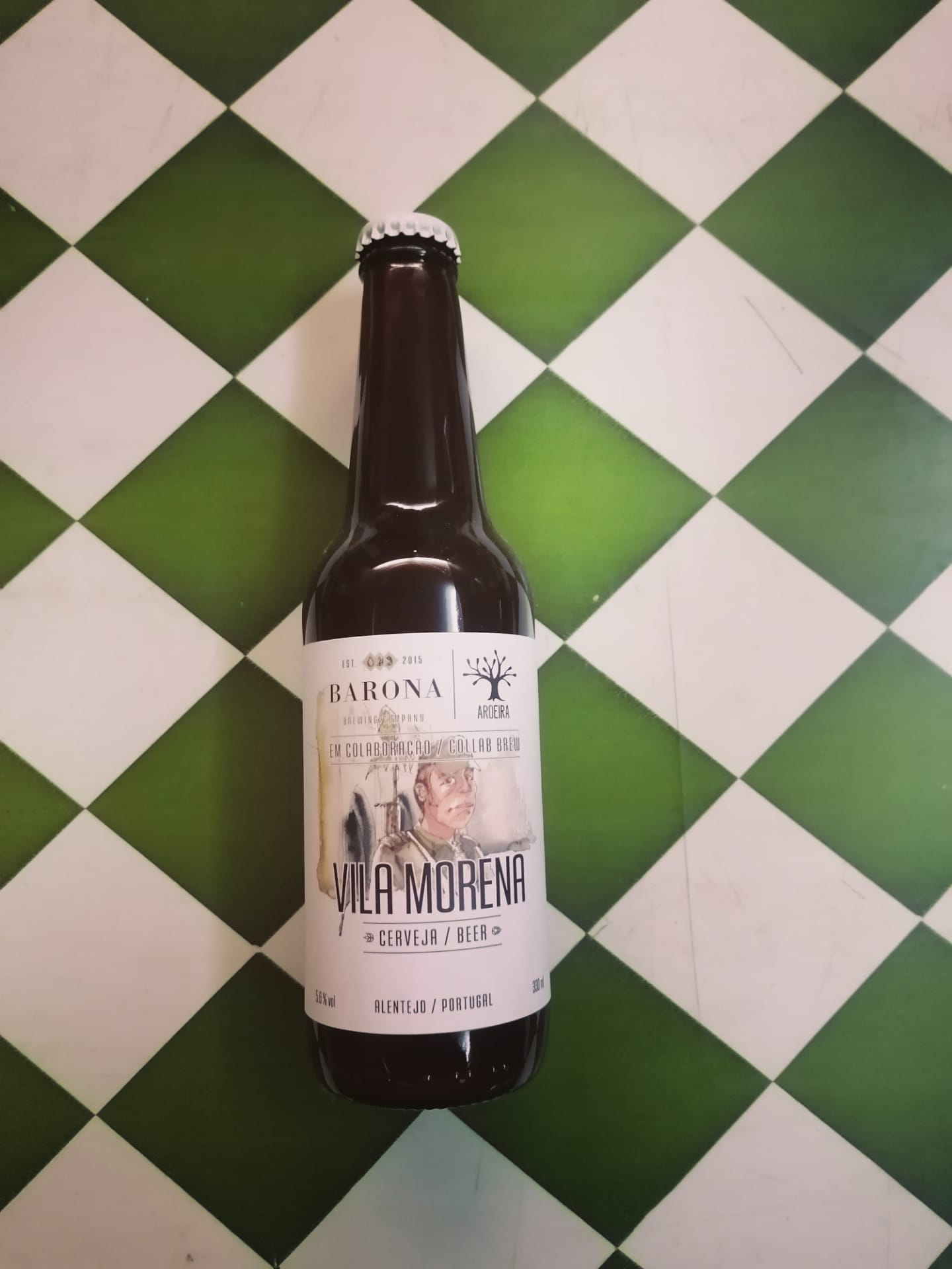 Barona Vila Morena Garrafa de cerveja Vila Morena com rótulo branco sobre azulejos verdes e brancos