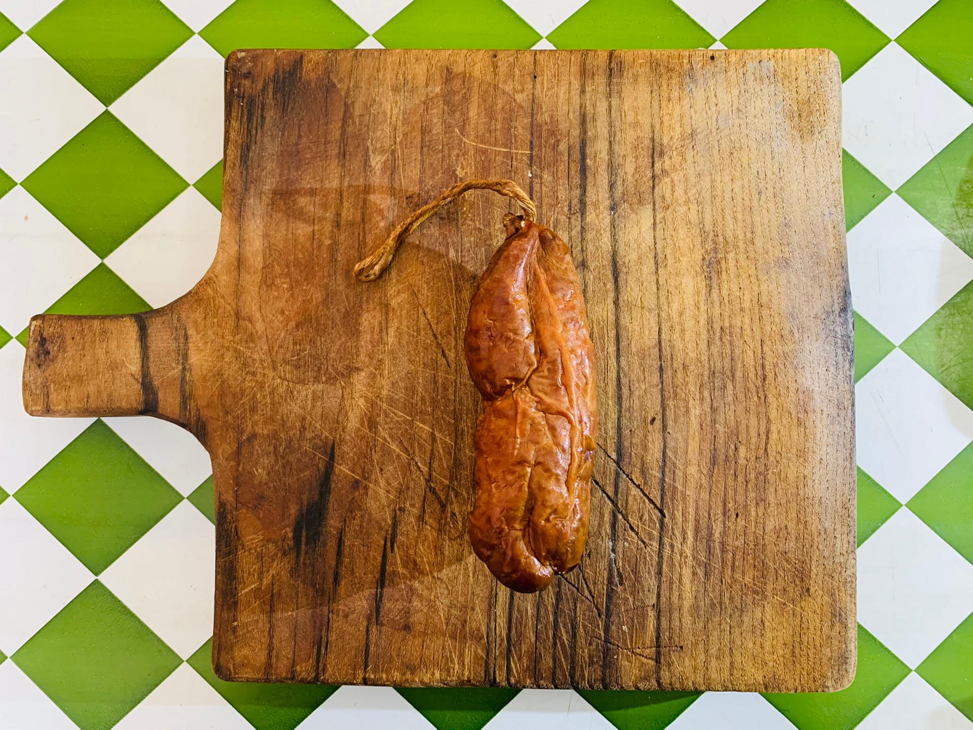 Painho Chouriço numa tábua de madeira sobre azulejos verdes e brancos